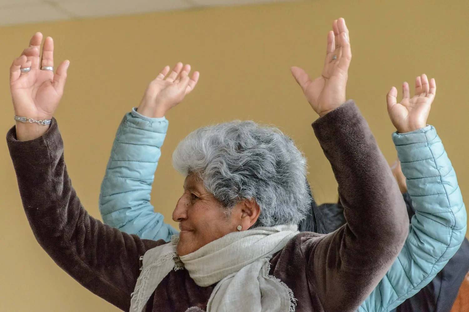 Adultos mayores participando en taller grupal con brazos levantados